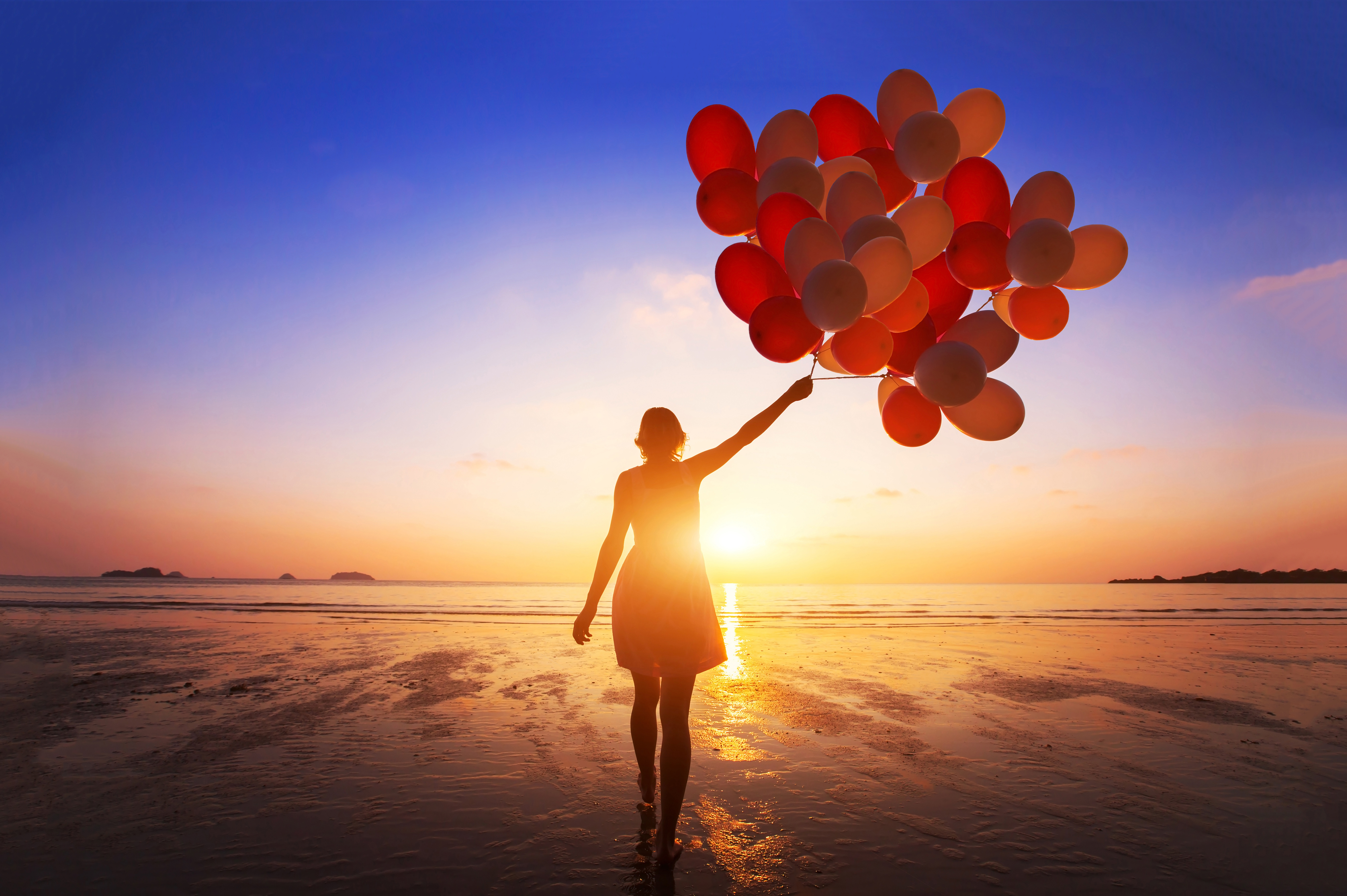 inspiration, joy and happiness concept, silhouette of woman with many flying balloons on the beach